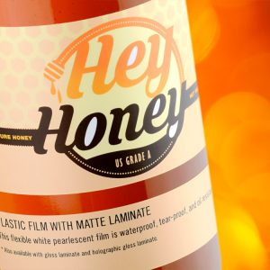Custom plastic film label sample showing honey print artwork on plastic film stock with matte laminate
