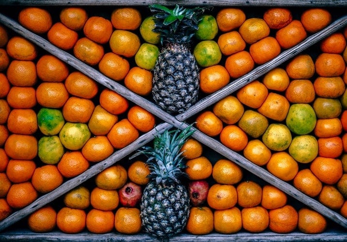 Pineapples stand out as unique in this frame of similar apples and oranges!