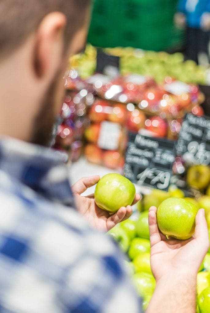 Man Looking at Two Green Apples