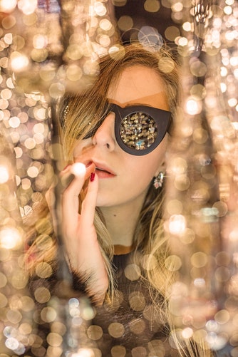 Woman wearing glasses reflecting gold with gold bokeh